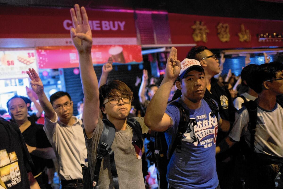 Hong Kong students show the three-finger salute from the "The Hunger Games" in the Mong Kok district on Nov. 29, 2014.