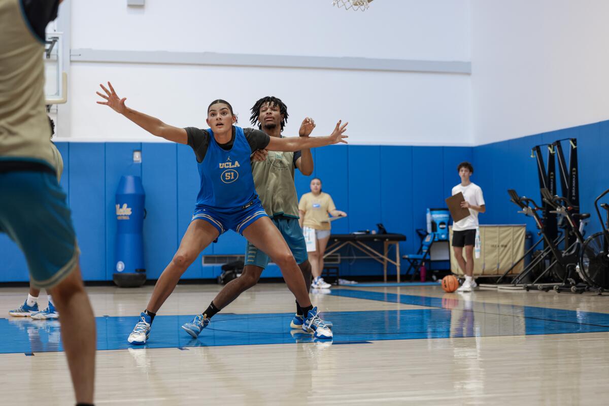 UCLA's Lauren Betts spreads her arms and posts up in front of a male practice player during a preseason workout.