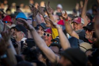 Pasadena, CA - May 14: A fan wearing a Devo hat joins others in the crowd cheering for Devo as they perform at the Cruel World festival at Rose Bowl in Pasadena on Saturday, May 14, 2022. (Allen J. Schaben / Los Angeles Times)