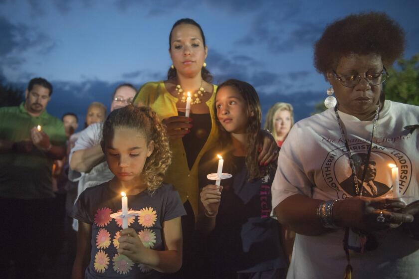 From left, Amora DeVries, 7, Afira DeVries, Eva DeVries, 9, and Brenda Keeling of Roanoke show their support for two slain TV journalists at a candlelight vigil in front of the studios of WDBJ-TV in Roanoke, Va.