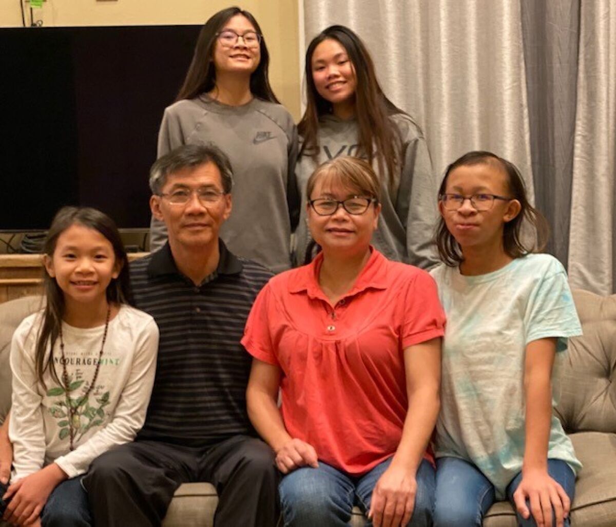 Michael Nguyen sits with his wife and four daughters.