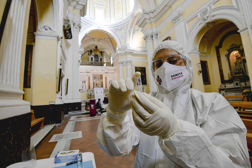 A medical operator prepares to perform COVID-19 test swabs in the Church of San Severo Outside the Walls, in the heart of Naples, Italy, Wednesday, Nov. 18, 2020. An initiative of "Sanita' Diritti Salute" association and the San Gennaro Foundation, aimed at helping those who cannot afford the cost of a private test, also allows, in the best tradition of Naples, those who want to pay 18 euros for a "suspended swab", to be taken by somebody else, exactly as it happens for the famous Neapolitan "suspended coffee". (Alessandro Pone /LaPresse via AP)