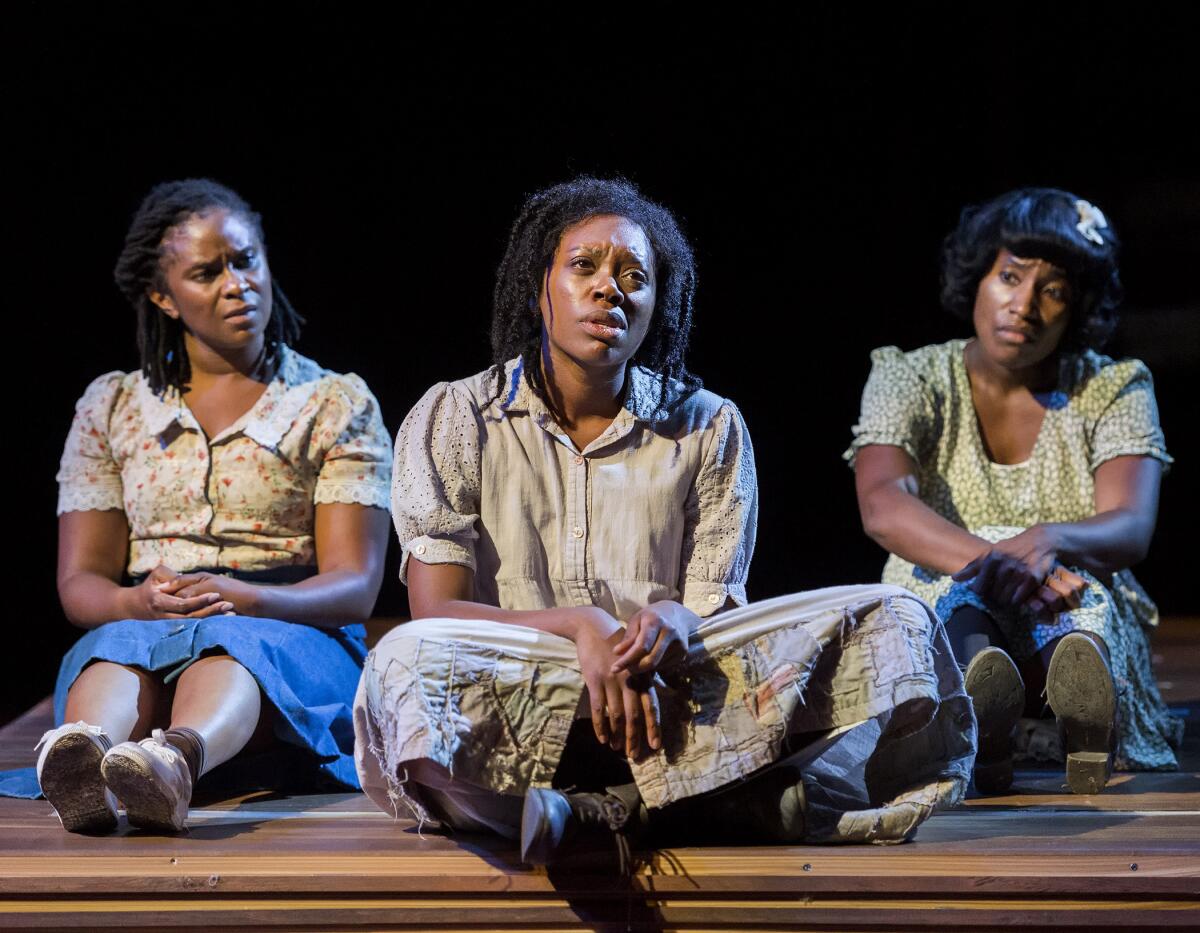 Three Black women sit in a line on a stage