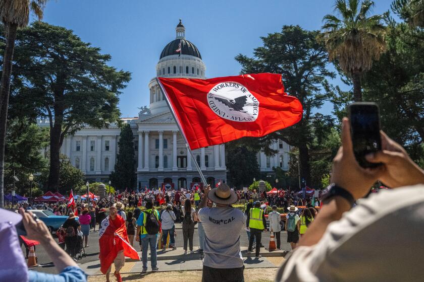 Joe Aguilar of Sacramento waves a United Farm Workers flag in front of the state Capitol in Sacramento after the union finished a 24-day march on Friday, Aug. 26, 2022, to call on Gov. Gavin Newsom to sign a bill that would give farmworkers the ability to vote from home to unionize.