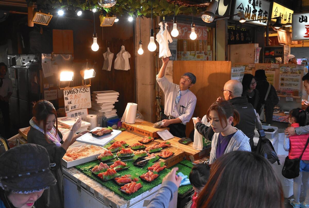 Customers gather around a seafood shop near the Tsukiji Fish Market in Tokyo. Japan's economy has slipped into recession for the fifth time in seven years.