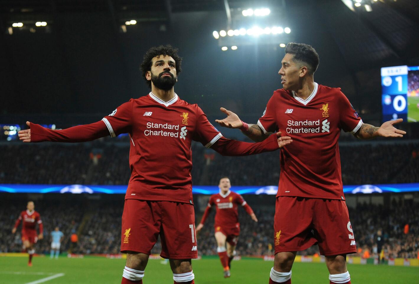 Mohamed Salah (izquierda) del Liverpool festeja tras anotar el primer gol de su equipo junto a Roberto Firmino en el partido contra Manchester City en los cuartos de final de la Liga de Campeones, en Manchester, el martes 10 de abril de 2018.