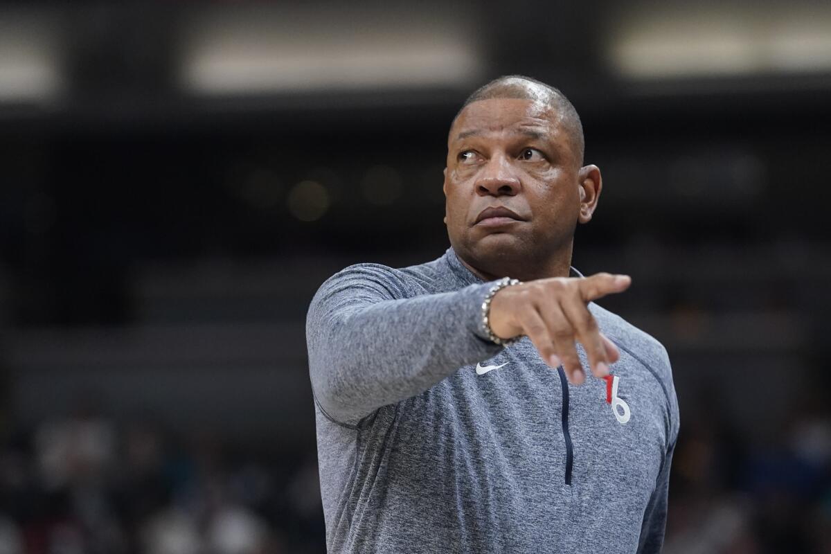 Doc Rivers points toward the court while coaching from the sideline of a game for Philadelphia.