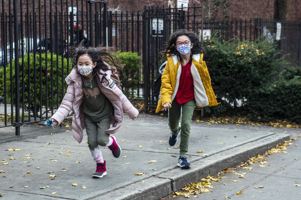 FILE — Students wearing masks leave the New Explorations into Science, Technology and Math (NEST+m) school in the Lower East Side neighborhood of Manhattan, Dec. 21, 2021, in New York. New York City public school students will be allowed to remove their masks outside starting next week but must keep them on indoors for now. Schools Chancellor David Banks announced the new policy in a news release Friday, Feb. 25, 2022. (AP Photo/Brittainy Newman, File)