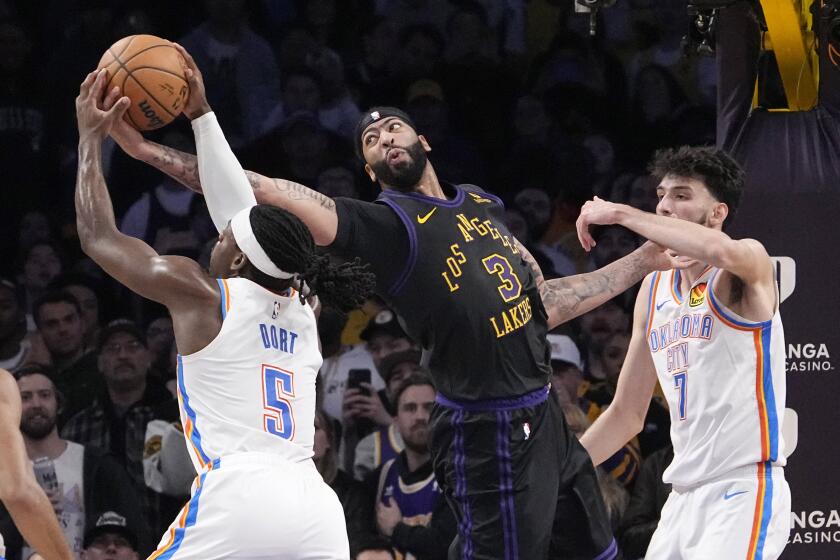 Oklahoma City Thunder guard Luguentz Dort, left, and Los Angeles Lakers forward Anthony Davis, center, each for a rebound as forward Chet Holmgren stands by during the second half of an NBA basketball game Monday, Jan. 15, 2024, in Los Angeles. (AP Photo/Mark J. Terrill)