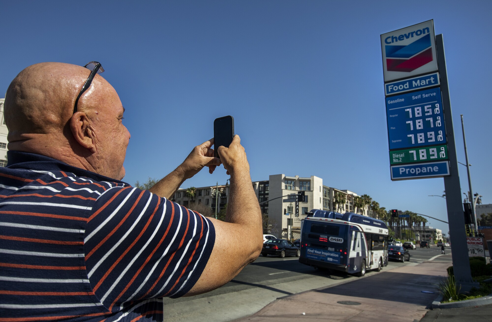 A man takes a photograph of the sign showing the price of gasoline in downtown L.A.