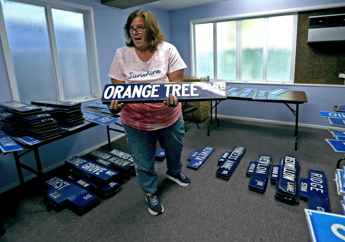 Maureen Bond shows off old street signs that were auctioned off in August 2019 to raise funds for the Community Center of La Cañada Flintridge. On Nov. 7, Bond resigned from CCLCF after five years of service.