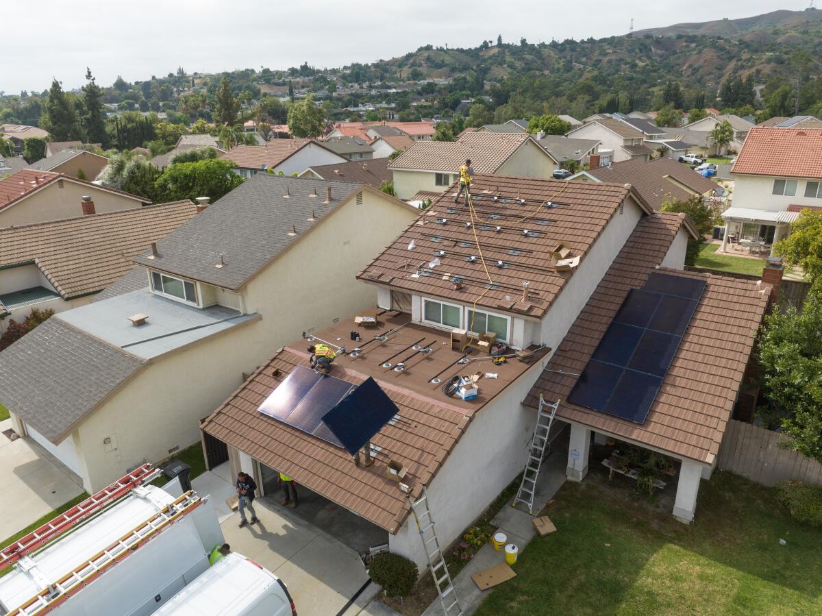 Workers install rooftop solar panels on a house in Brea on June 15.