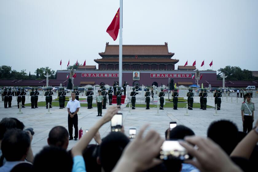 Chinese paramilitary police stand watch as visitors observe the flag-lowering ceremony on the eve of the June 4 anniversary of the 1989 crackdown on pro-democracy demonstrators at Tiananmen Square in Beijing.