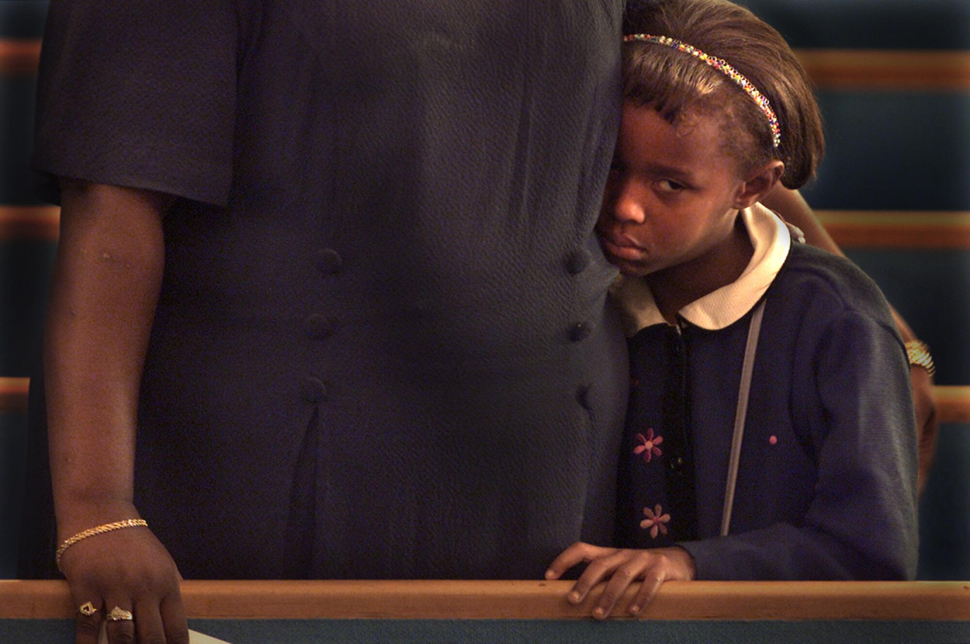 A young girl stands next to her grandmother in church