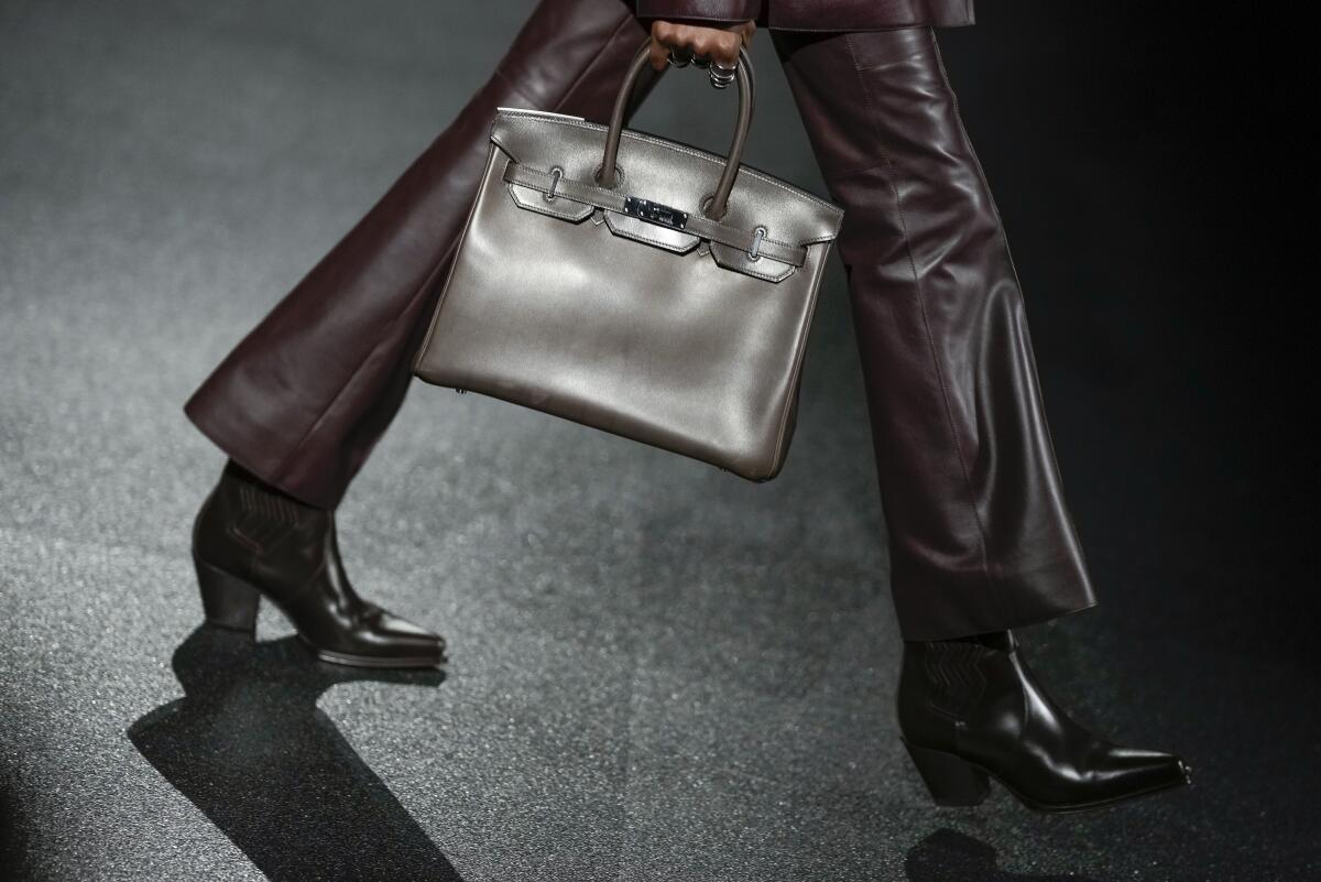 A model carries a bag in a Hermès show.