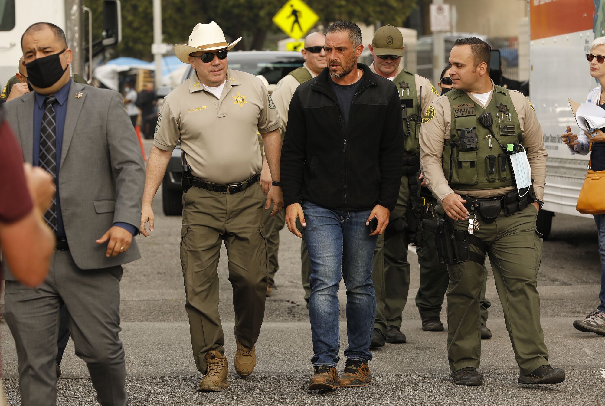 Robert Reynolds, center, a veteran advocate with Amvets, walks with L.A. County Sheriff Alex Villanueva.