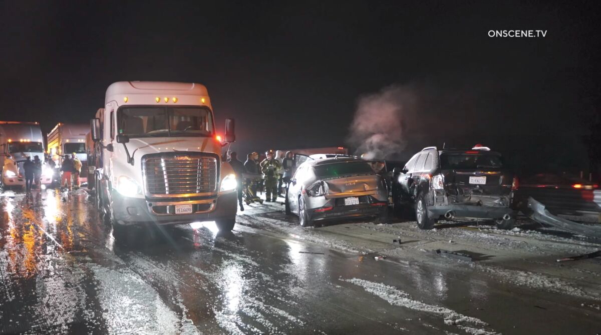 Big rigs next to crashed vehicles on a wet, icy road