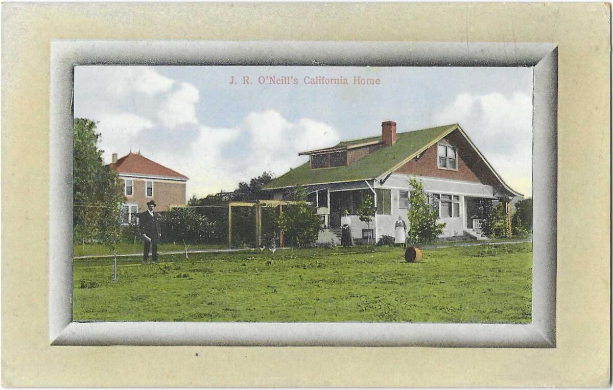 A man and two women stand in front of a home bordered by a lawn.