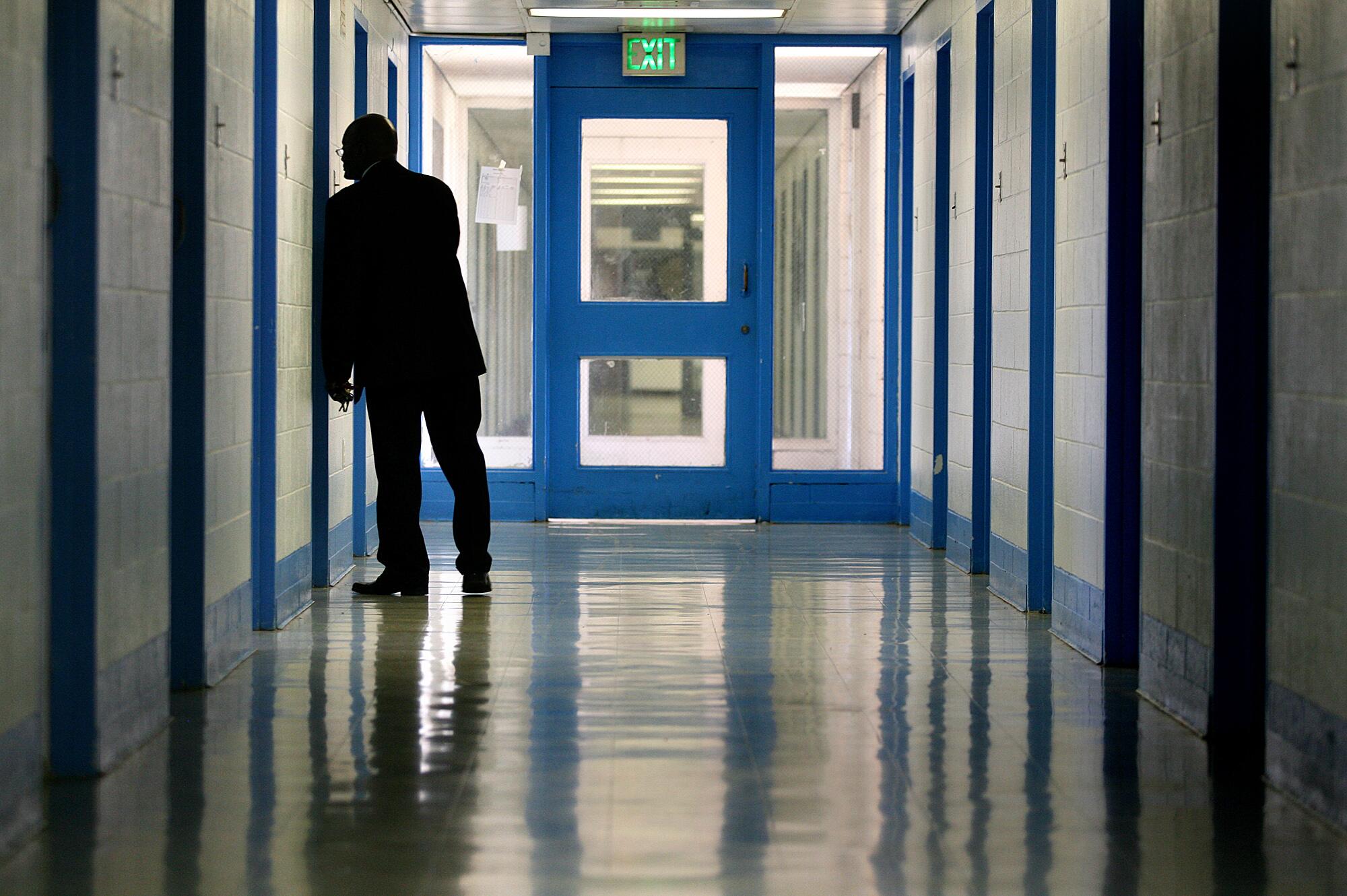 A person in silhouette looking into a room from a hallway