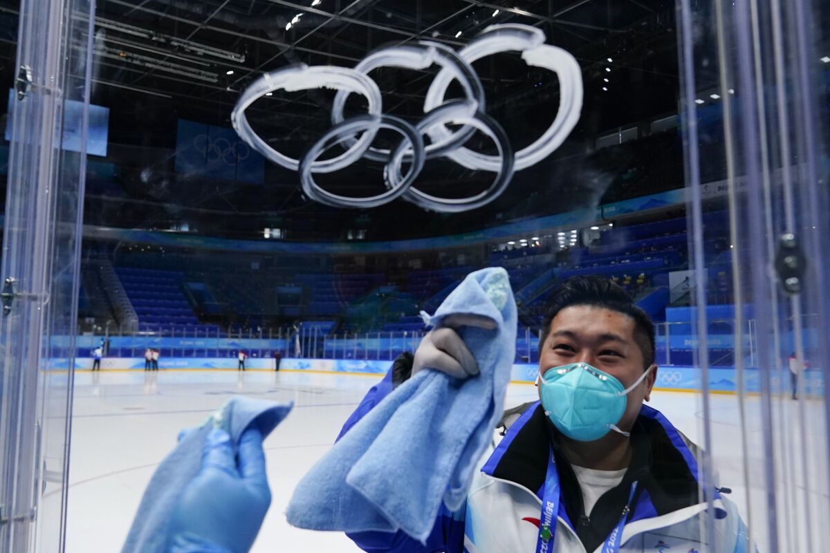 A worker sprays the Olympic rings with cleaner as he cleans the glass at the hockey venue.