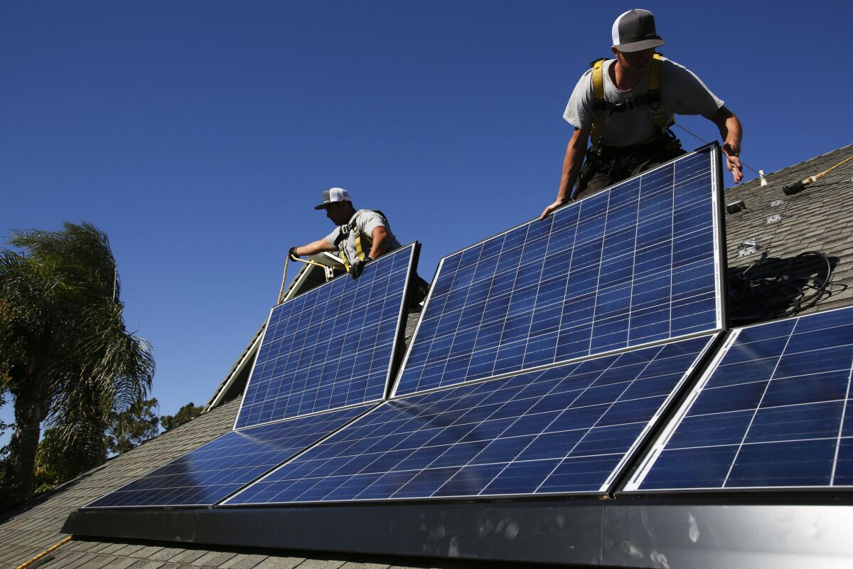 Jobs in the U.S. solar industry grew 21.8% in 2014 as the price of panels fell and demand grew. Above, Rogelio Mora, left, and Tyler Smith, workers from vivint.solar, install solar panels on the roof of a home in Camarillo.