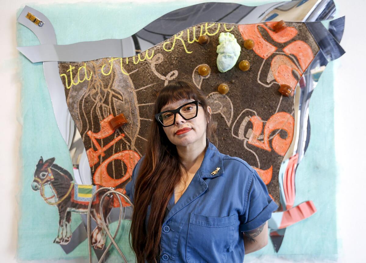 Santa Ana artist Lorena Ochoa stands with "Somos de Calle Diptych." 