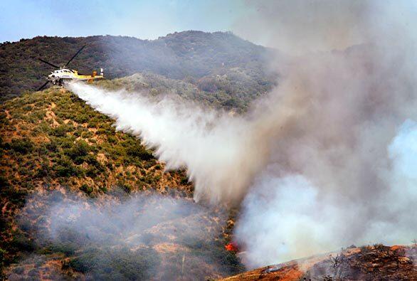 Firefighters work to contain the fire in a canyon with water drops. On Monday, about half of the 500-acre fire was in the Angeles National Forest and half within the boundaries of Sierra Madre.