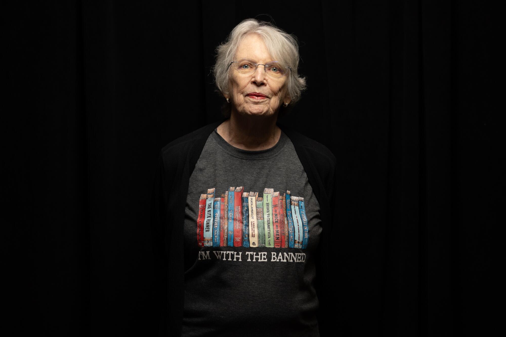 A woman appears against a black background wearing a T-shirt with books and the words "I'm with the banned."