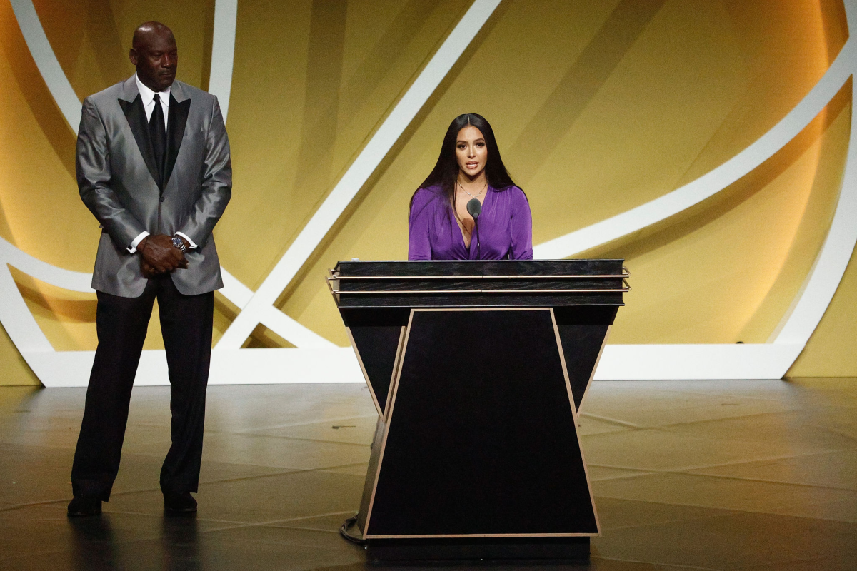 Vanessa Bryant speaks at a podium. At left is Michael Jordan