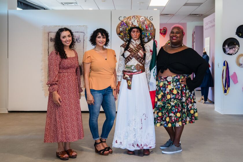 Artists Ines Nefzi (second to left), Karla Burner (left) and Poet Kelsey Daniels (right) pose for a photo with "Las Soldaderas" mannequin honoring the women who traveled with the male soldiers during the Mexican Revolution at Joe and Vi Jacobs Center in Encanto on August 22, 2022.