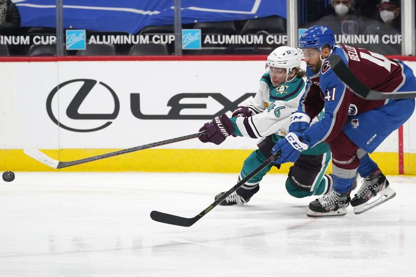 Anaheim Ducks center Trevor Zegras, left, reaches out for the puck as Colorado Avalanche center Pierre-Edouard Bellemare defends during the third period of an NHL hockey game Tuesday, March 16, 2021, in Denver. The Avalanche won 8-4. (AP Photo/David Zalubowski)