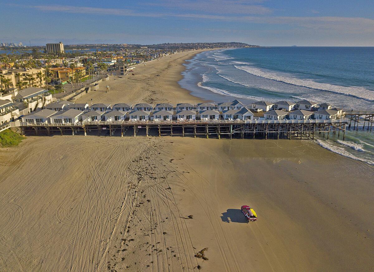 A San Diego Lifeguard patrols an empty Pacific Beach at Crystal Pier, March 24, 2020. San Diego beaches and parks were closed since the end of March by emergency City and County regulations to stop people from gathering and help slow the spread of coronavirus.