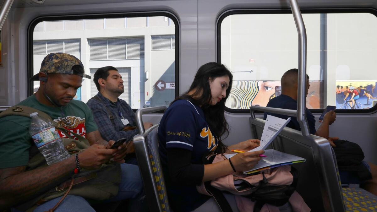 High school senior Yecenia Perez, 17, does her homework on the train after school. Being paired with a mentor lets her share her struggles at home and worries about college with someone who's been there.