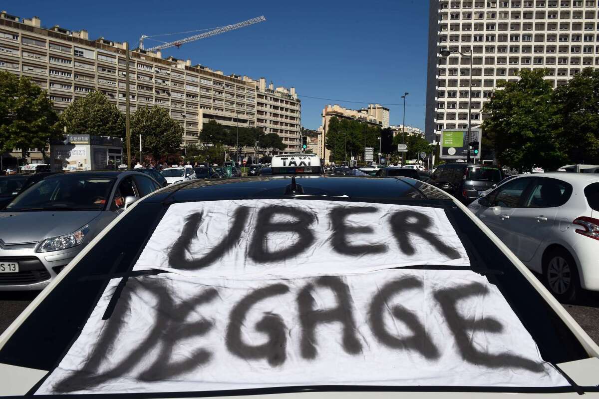 A banner that translates as "Uber get out" is displayed across a taxi windshield during a June 25 protest in Marseille, France, as taxi drivers demonstrated against UberPop, a popular taxi app that is facing fierce opposition from traditional cabs.