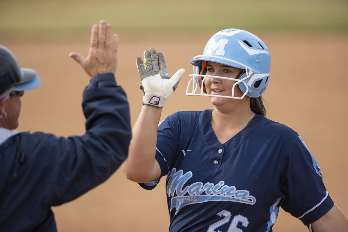 Marina's Emily Rush gets a high-five from Vikings coach Shelly Luth after getting on base in a Surf League game at Edison on April 11, 2019.