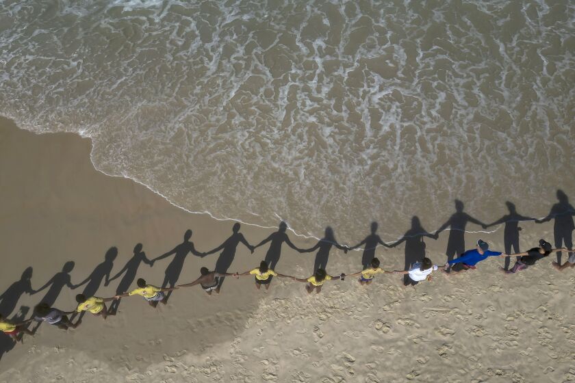 People create a line holding hands along Sao Conrado beach for a symbolic group hug with the sea on World Oceans Day in Rio de Janeiro, Brazil, Thursday, June 8, 2023. The Route Brasil environmental organization called for people to gather for the event coined "That Hug" to draw attention to ocean pollution. (AP Photo/Bruna Prado)
