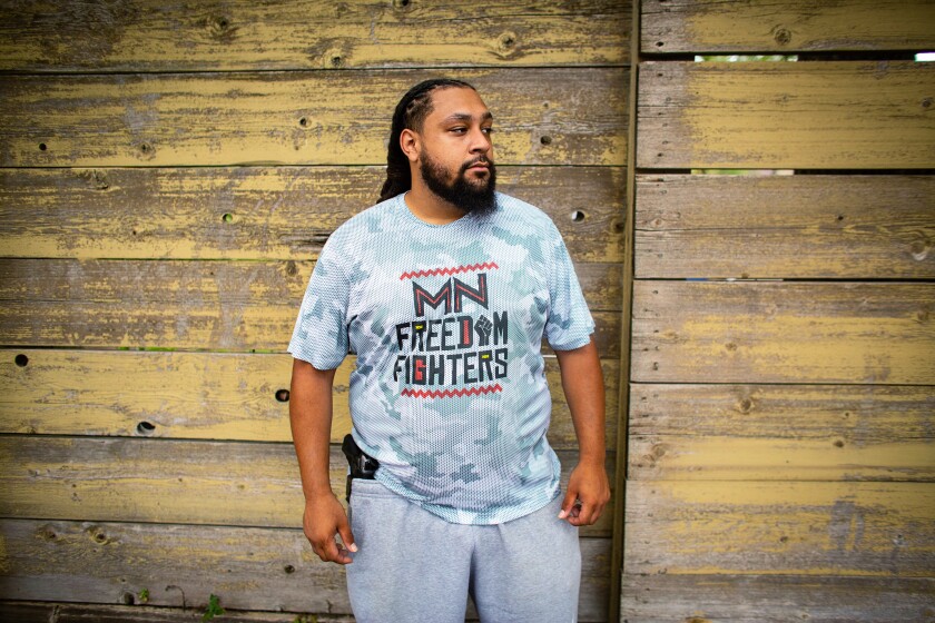 MINNEAPOLIS, MN - JULY 25: Romeal Taylor, a member of the Minnesota Freedom Fighters, sheds his riffle and tactical vest, only carrying a hand gun, at the meet-and-greet event to connect with the community on Saturday, July 25, 2020 in Minneapolis, MN. (Jason Armond / Los Angeles Times)