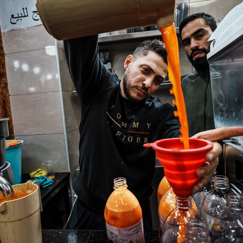 A man prepares bottles of fresh carrot juice, a staple for Iftar meals