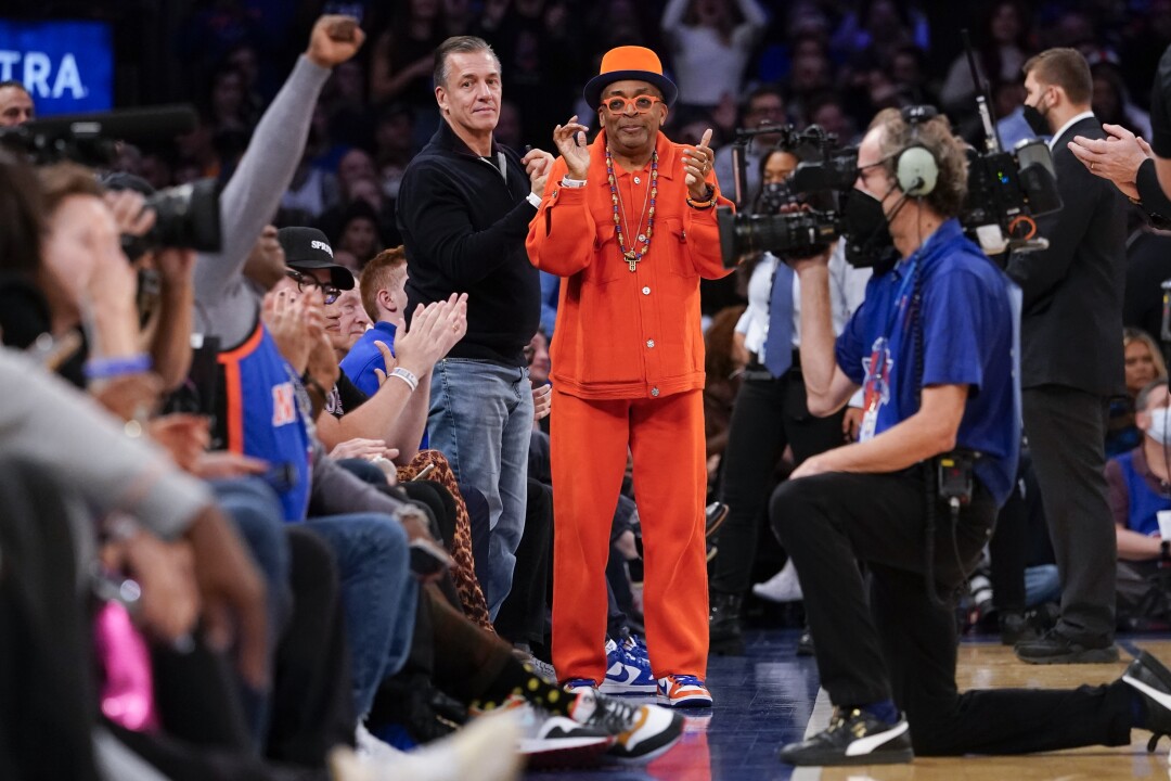 Film director Spike Lee, center, claps during a time out in the first half of an NBA basketball 