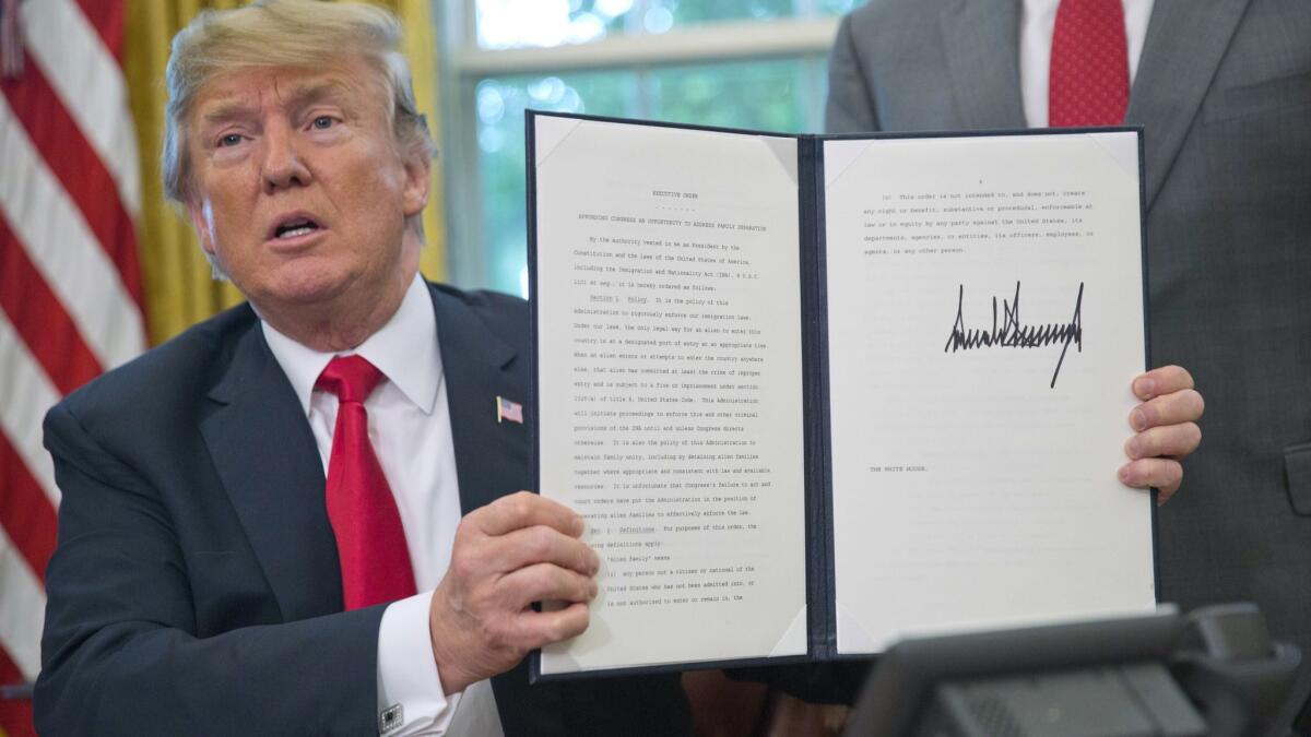 President Trump holds up the executive order he says will end family separations at the border.