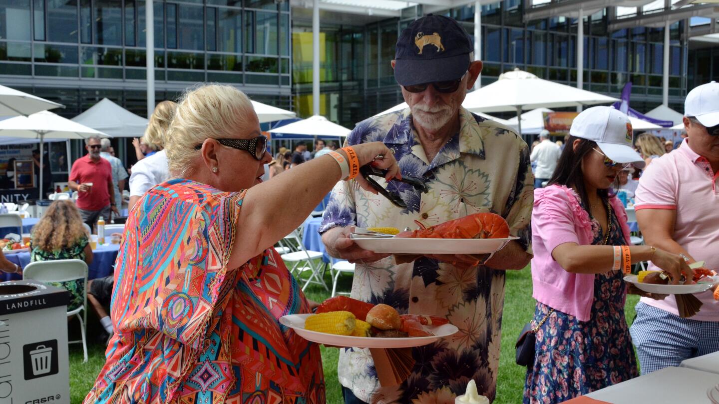 Agnes Szabo places corn on her husband John's plate at Lobsterfest on Sunday at the Newport Beach Civic Center green.