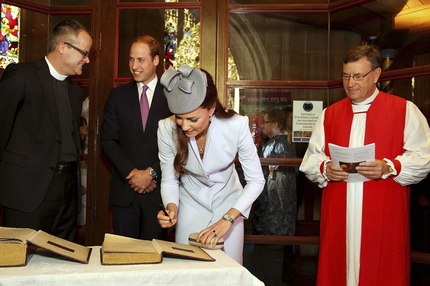 Kate, the Duchess of Cambridge, signs the First Fleet Bible and Prayer Book as the Most Rev. Glenn Davies, Archbishop of Sydney, right, watches after an Easter Sunday service at St. Andrews Cathedral.