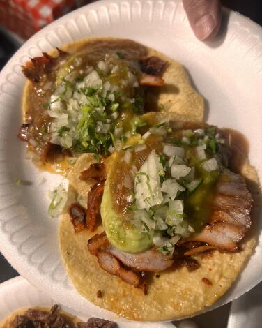 A pair of al pastor tacos with toppings