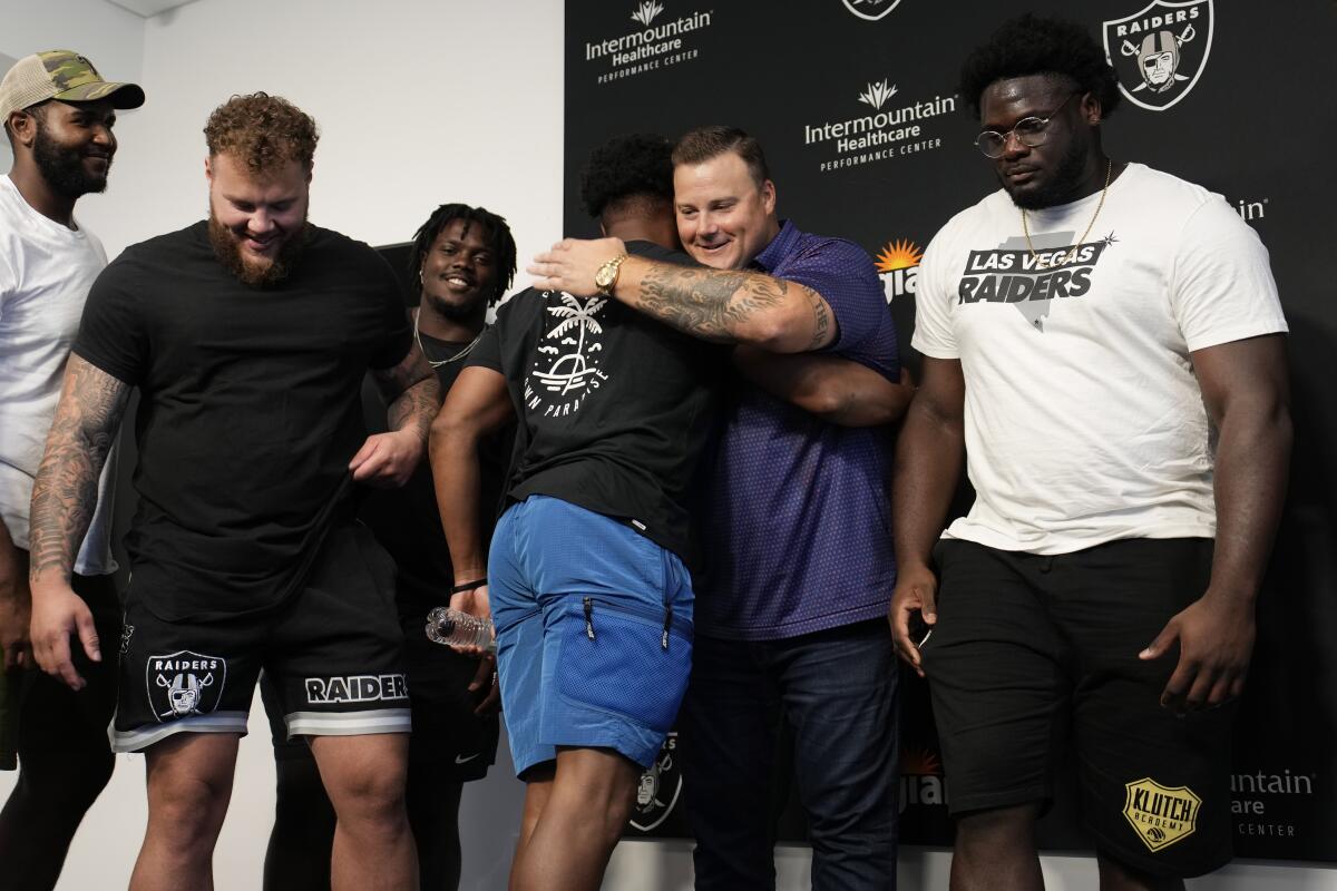 Las Vegas Raiders guard Richie Incognito, second from right, embraces Kenyan Drake at a news conference announcing Incognito's retirement, Friday, July 15, 2022, in Henderson, Nev. (AP Photo/John Locher)