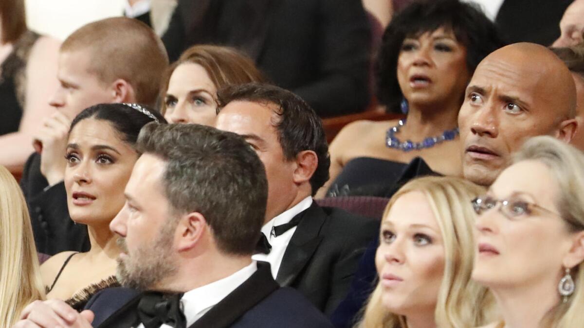 Meryl Streep, right, and Dwayne Johnson react with arched eyebrows. Sitting behind the Rock is motion picture academy President Cheryl Boone Isaacs.