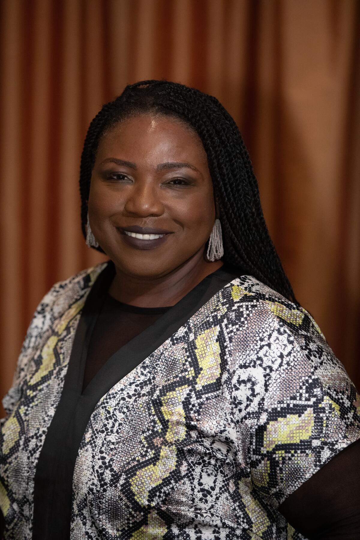 A smiling woman in a snakeskin-print shirt