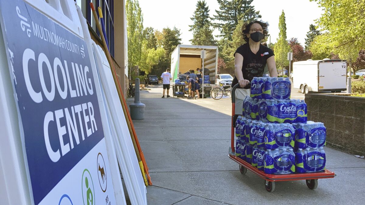 FILE - A volunteer helps set up snacks at a cooling center established to help vulnerable residents ride out a dangerous heat wave on Aug. 11, 2021. The historic heat wave, which toppled all-time temperature records, killed more than 200 people in Oregon and Washington. Now, lawmakers in the Pacific Northwest are eyeing several emergency heat relief bills aimed at helping vulnerable populations. The proposed measures would provide millions in funding for cooling systems and weather shelters during future extreme weather events. (AP Photo/Gillian Flaccus, File)