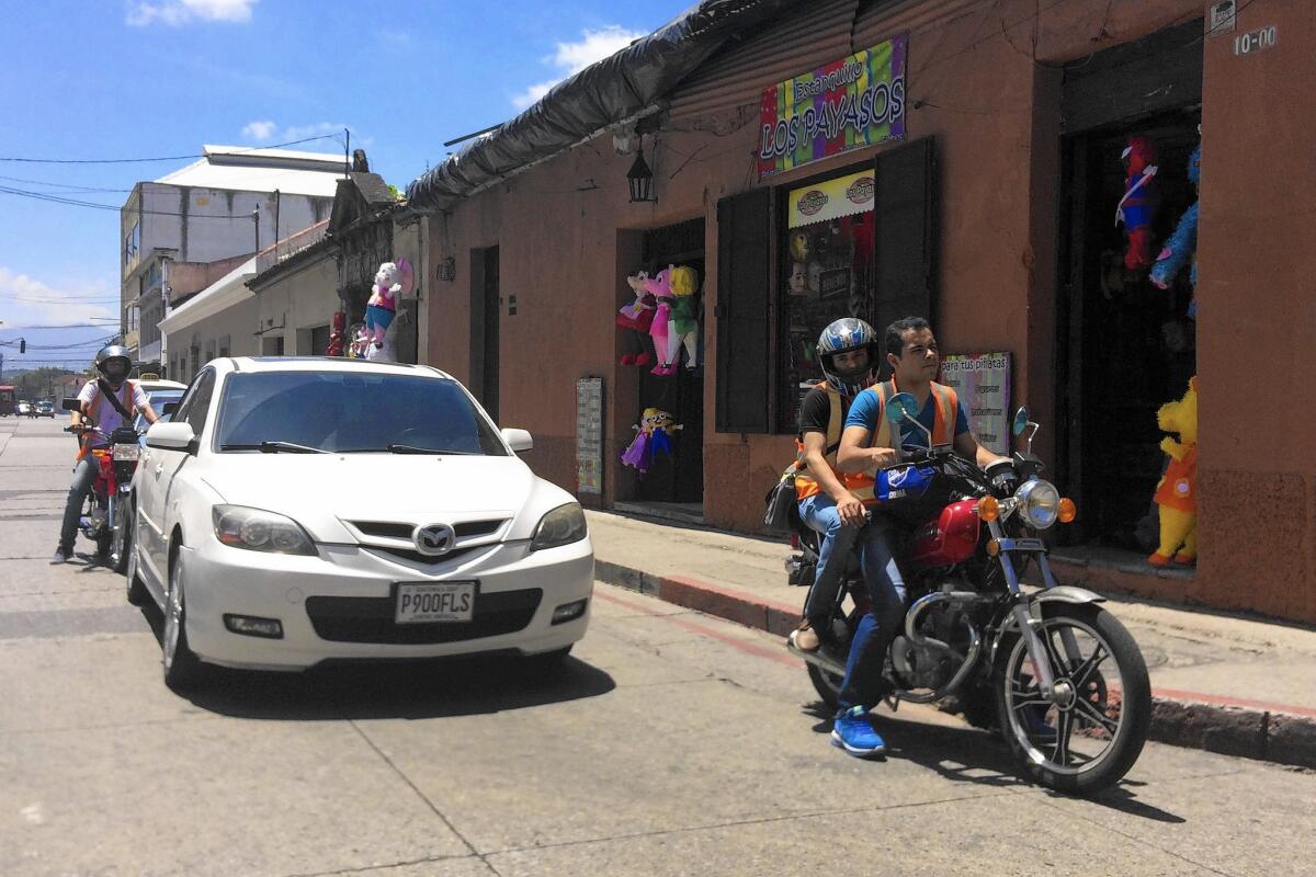 A motorcyclist speeds by shops in Guatemala City's Zone 1, the historic center. The municipality is divided into zones that spiral out from Zone 1.