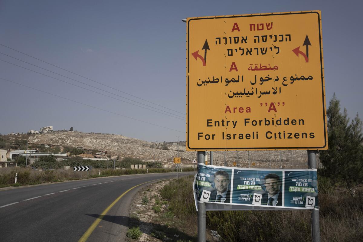 FILE - Campaign posters for far-right Israeli lawmaker Bezalel Smotrich, now the Minister of Finance, is strung across a road sign marking an entrance to an area under Palestinian control, near the West Bank town of Nablus, Sunday, Oct. 16, 2022. Smotrich assumed new powers from the military over the occupied territory this year. As the first minister to oversee civilian life in the West Bank, his role amounts to a recognition that Israel's occupation is not temporary, but permanent, observers say. (AP Photo/ Maya Alleruzzo, File)