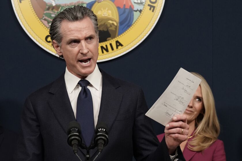 FILE - California Gov. Gavin Newsom displays a bill he signed that shields abortion providers and volunteers in California from civil judgements from out-of-state courts during a news conference in Sacramento, Calif., June 24, 2022. Newsom is headed to Washington this week, providing him with a national stage to continue his outspoken defense of abortion rights and gun control while lambasting Republican-led states that he sees as a threat to personal freedom and public safety. (AP Photo/Rich Pedroncelli, File)